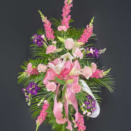 Pink and purple funeral spray with lilies and roses on a stand