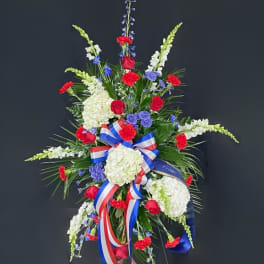 Standing floral spray with red roses, white hydrangeas, and blue accents