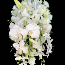 Cascading white bouquet with orchids, lilies, and roses against a black background