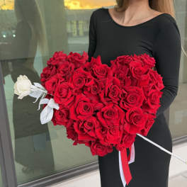 Heart-shaped bouquet of red roses with a single white rose