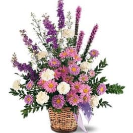 Basket arrangement of pink and purple flowers with white blooms