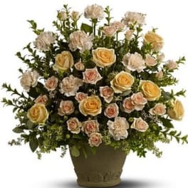 Arrangement of pale roses and carnations in a brown pot