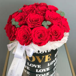 Red roses arranged in a black box with white ribbon