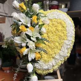 Heart-shaped floral wreath with white lilies and yellow roses