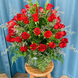 Red roses arranged in a green vase with airy filler flowers