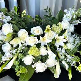 White roses and lilies arranged with pale green accents