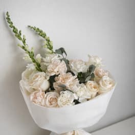 Cream and blush bouquet wrapped in white paper with a lace ribbon