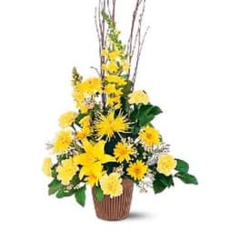 Tall yellow floral arrangement in a brown basket with branches