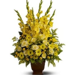 Tall yellow floral arrangement in a brown urn vase