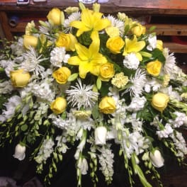 Yellow lilies and roses arranged with white flowers in a large spray
