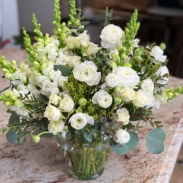 White flowers and green spikes arranged in a clear glass vase