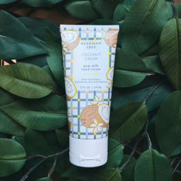 Tube of coconut cream goat milk hand cream on dark green leaves