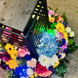 Colorful floral arrangement around a black lantern on the floor