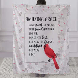 Person holding a quilt with an "Amazing Grace" verse and red cardinal design