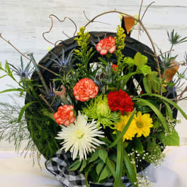 Mixed flower arrangement in a tire-shaped container with a checkered ribbon
