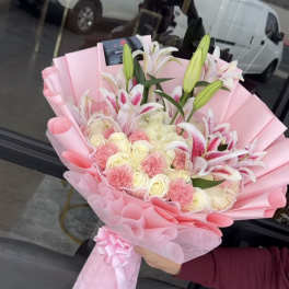 Pink-wrapped bouquet of lilies, roses, and carnations