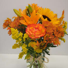 Orange and yellow bouquet in a glass vase with a raffia bow