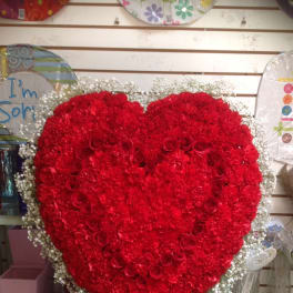Large heart-shaped red flower arrangement on an easel