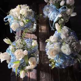 Four blue and white floral bouquets with ribbon on a wooden surface