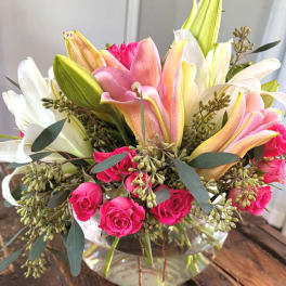 Pink and white lilies with hot pink roses in a glass vase