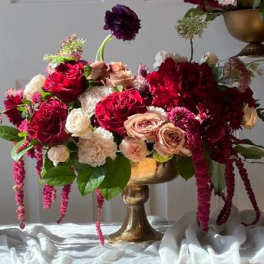 Arrangement of red, blush, and white roses in a gold vase