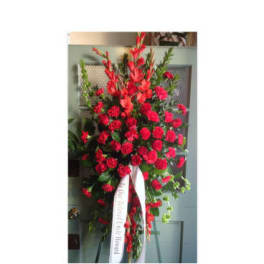 Tall standing spray of red carnations with a white ribbon