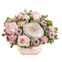 Pink roses and small purple flowers arranged in a round box with a lid