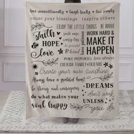Person holding a cream blanket with black inspirational text