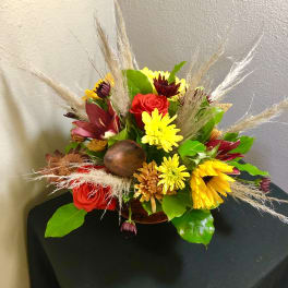 Mixed bouquet with red roses and yellow daisies in a low container