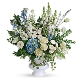 White and blue floral arrangement in a white pedestal vase