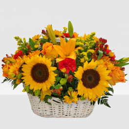 Basket arrangement with sunflowers, orange roses, and red flowers