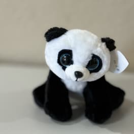 Small black-and-white plush panda toy sitting on a plain surface