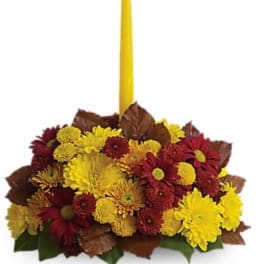 Yellow and red chrysanthemum arrangement with a tall yellow taper candle