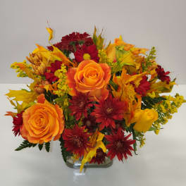 Orange and red flower arrangement in a clear glass vase