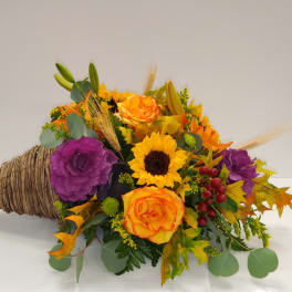 Cornucopia arrangement with sunflowers, roses, and purple cabbage flowers