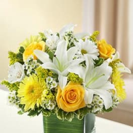 Yellow roses and white lilies in a green vase