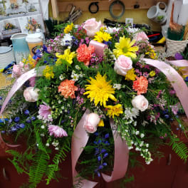 Large floral arrangement with pink roses, yellow daisies, and pink ribbons
