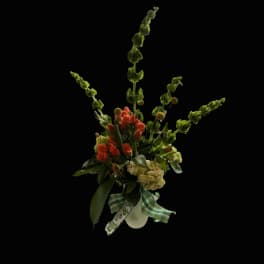 Tall floral arrangement with orange blooms and green spikes in a white vase
