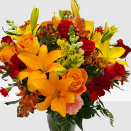 Mixed bouquet of orange and red flowers in a glass vase