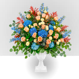 Large mixed floral arrangement in a white pedestal vase