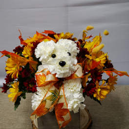 White teddy bear arrangement with autumn flowers and a leaf ribbon in a wooden base