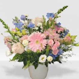 Pastel bouquet with pink gerbera, roses, and mixed blooms in a white vase
