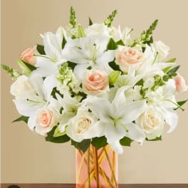 White lilies and pale peach roses in a glass vase