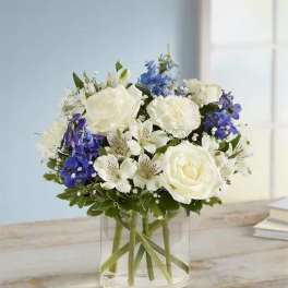 White and blue mixed flower bouquet in a clear glass vase