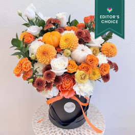 Orange and white floral arrangement in a black hatbox with a ribbon