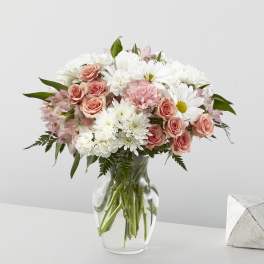 Pink roses and white daisies arranged in a clear glass vase