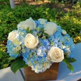 Blue hydrangea and white rose bouquet in a wooden box