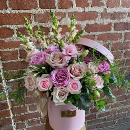 Pink and blush roses arranged in a pink hat box