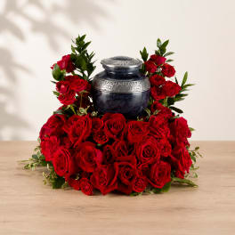 Red roses arranged around a dark urn-shaped vase