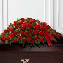 Red rose casket spray with ribbon on a dark casket